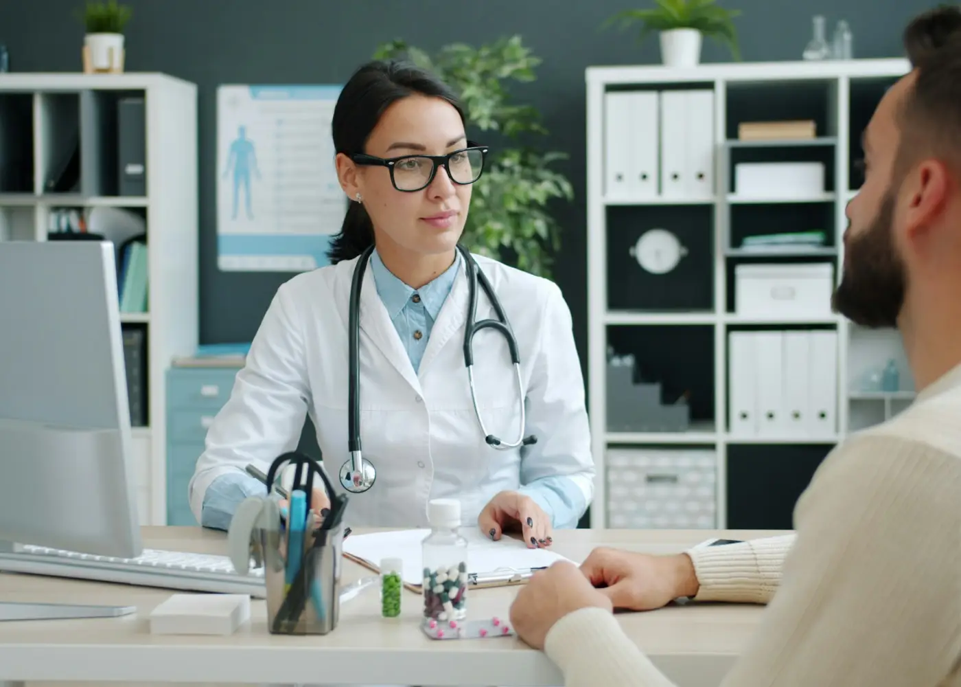 A doctor listening to a patient at her desk
